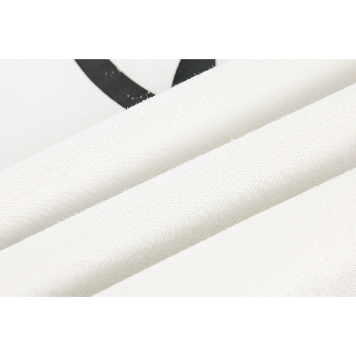 Close-up of folded white T-shirt fabric with part of a black print visible.