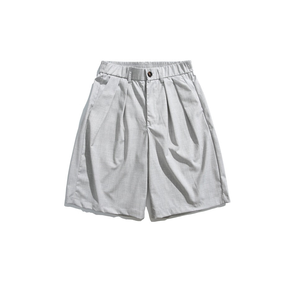 Front view of light gray pleated shorts with a button closure, belt loops, and side pockets.