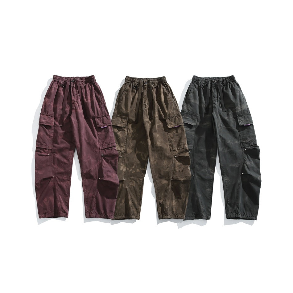 Three pairs of loose cargo pants displayed flat in burgundy, olive-brown, and charcoal colorways.