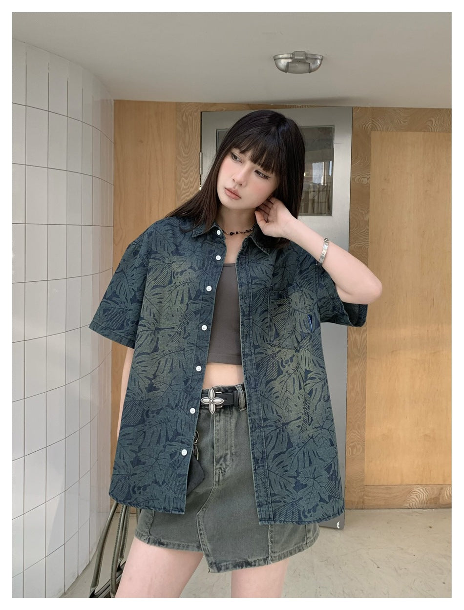 Front view of a model in an oversized blue-gray botanical-print short-sleeve shirt with white buttons and chest pocket.