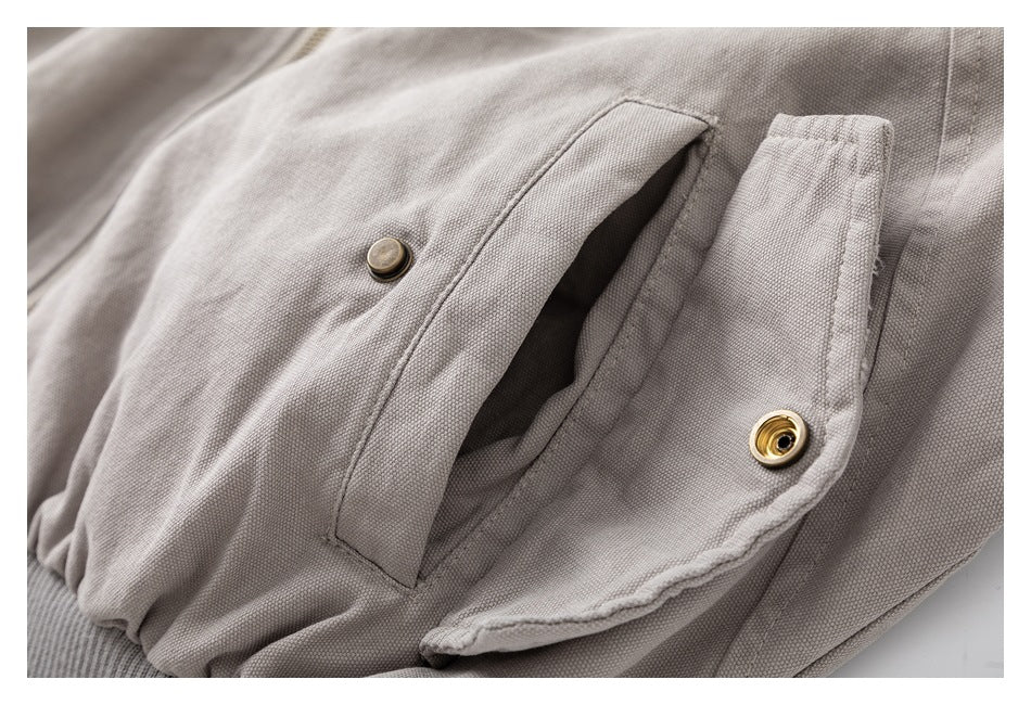 Close-up of a light taupe jacket pocket with antique-brass snap fasteners.