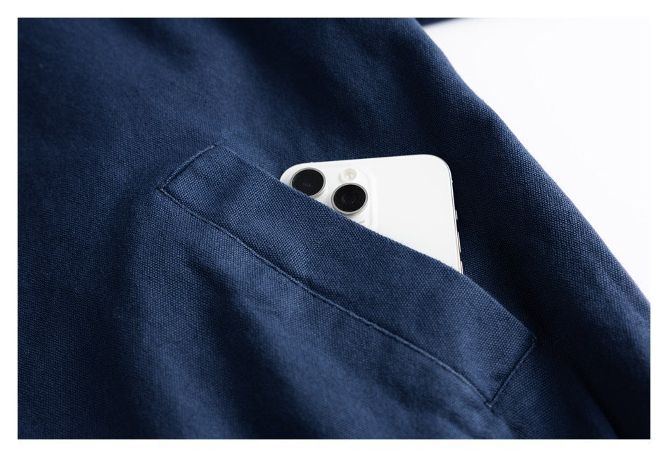 Close-up of a navy jacket's angled welt pocket holding a white smartphone.