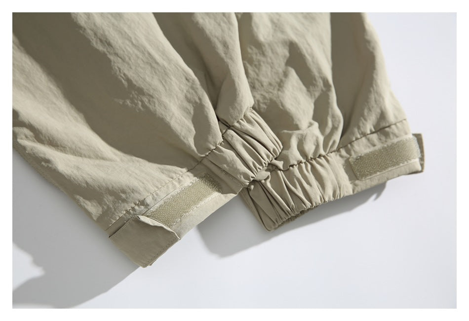 Close-up of beige trouser cuffs with gathered elastic sections and hook-and-loop adjustment tabs.