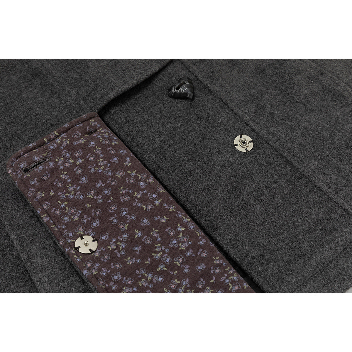 Close-up of the coat's floral inner placket lining, heart-shaped button, and metal snap fastener.