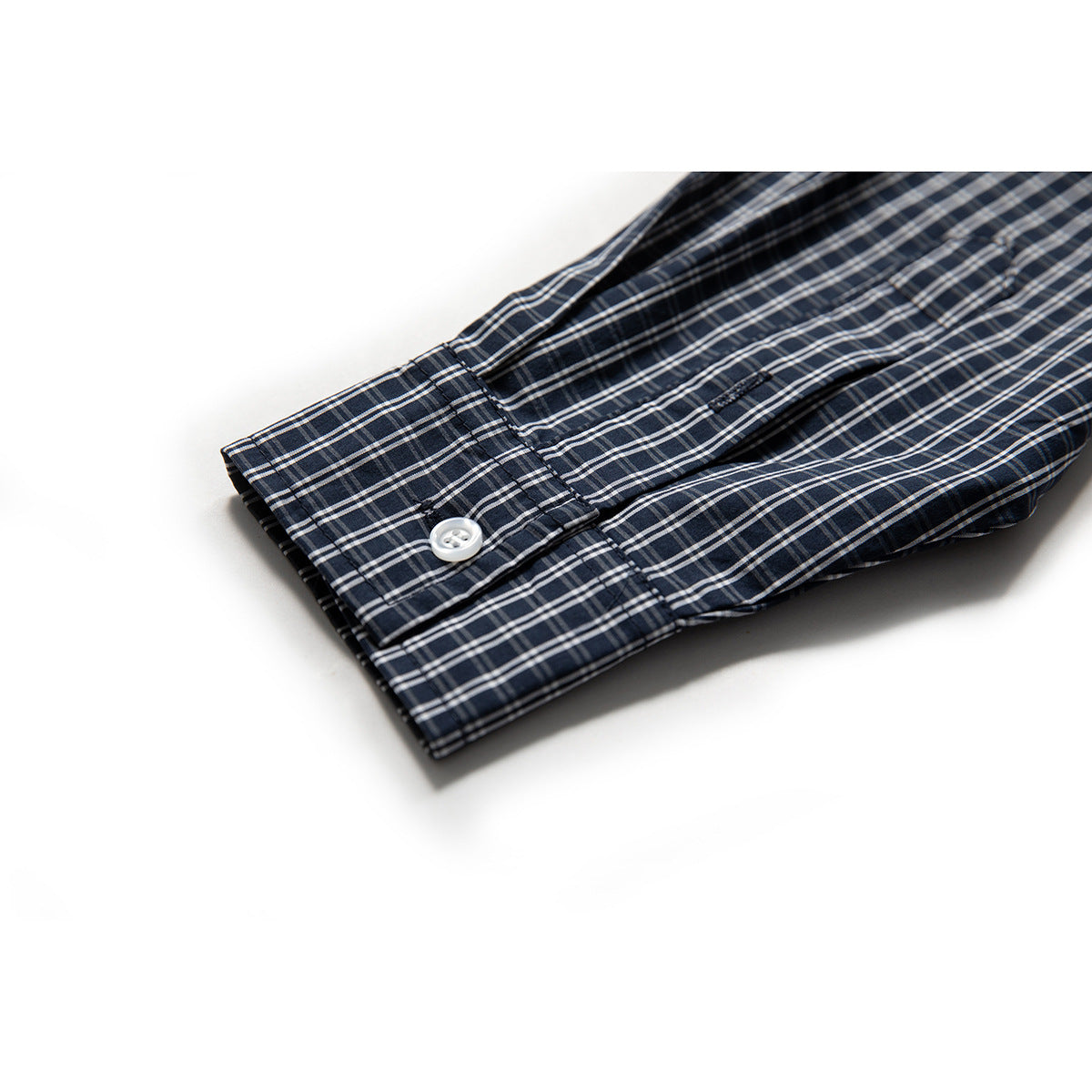 Close-up of a navy plaid shirt sleeve and buttoned cuff.