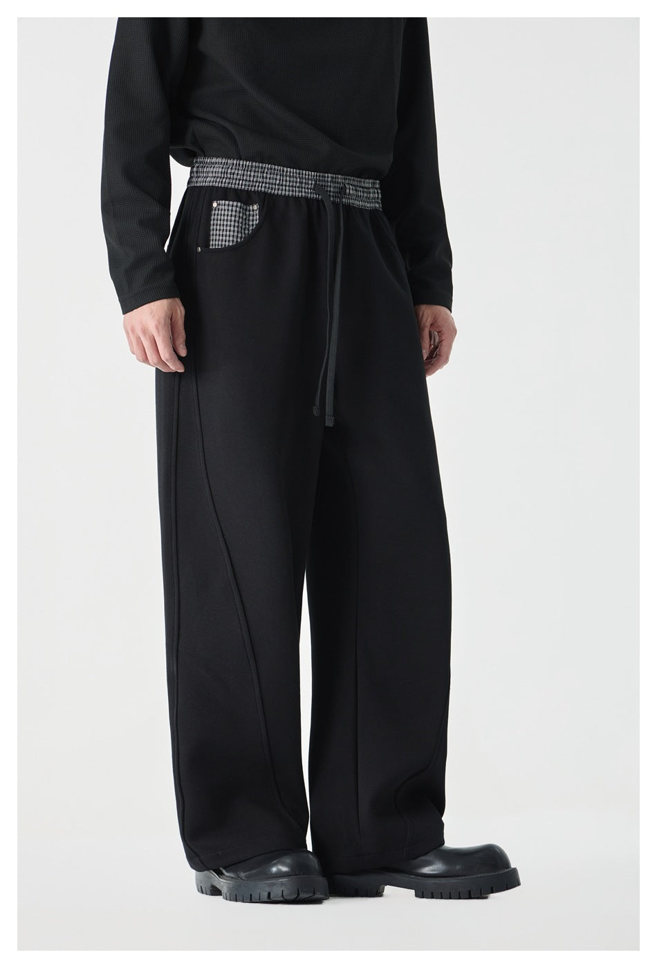 Model wearing black wide-leg pants with a checked elastic waistband, drawstring, and checked front pocket.
