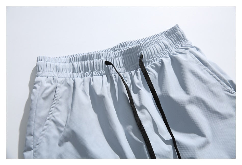 Close-up of pale blue-gray shorts showing a gathered elastic waistband and long black drawstrings.