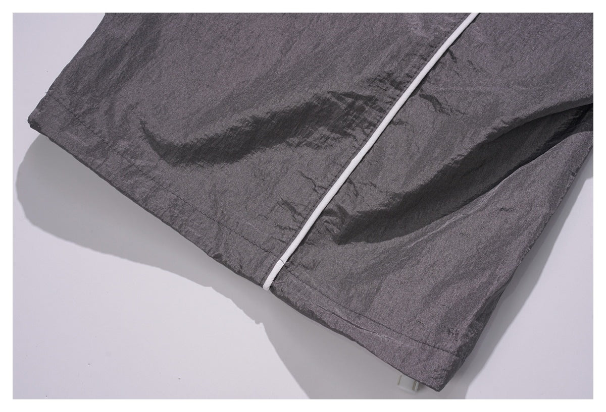 Close-up of dark charcoal garment hem with white piping and visible stitching.