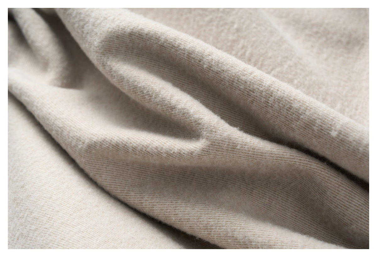 Close-up of softly draped light beige fabric with visible fine texture.