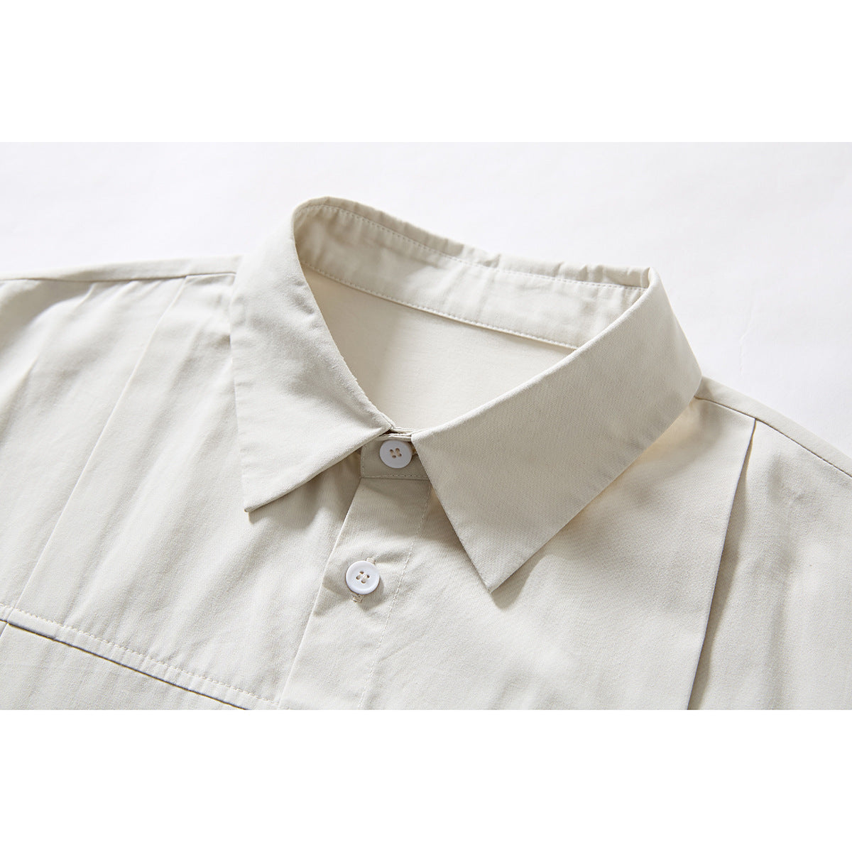 Close-up of an ivory shirt collar and upper button placket with white buttons and shoulder seams.