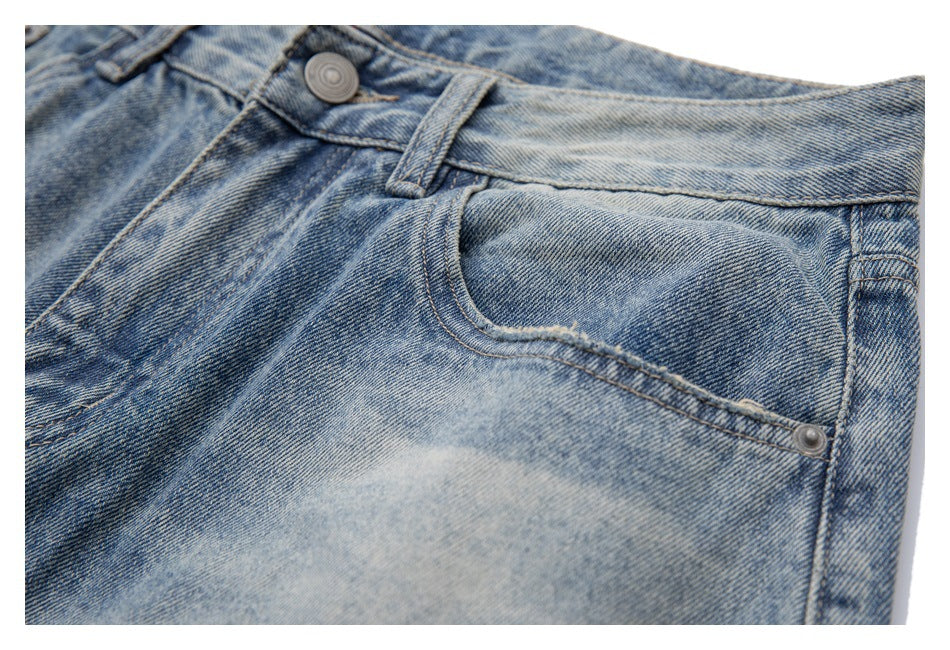 Close-up of light-wash blue jeans showing the curved front pocket, rivet, waistband, and belt loop.