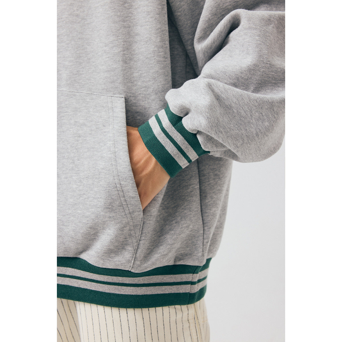 Close-up of the gray hoodie’s green-and-gray striped cuff, pouch pocket, and matching striped hem.