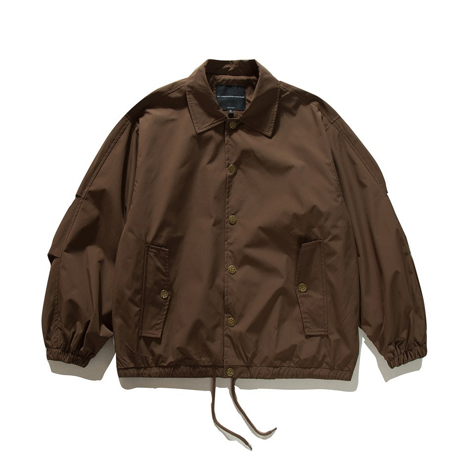 Brown coach-style jacket flat lay, front view with gold buttons, flap pockets, elastic cuffs and drawstring hem