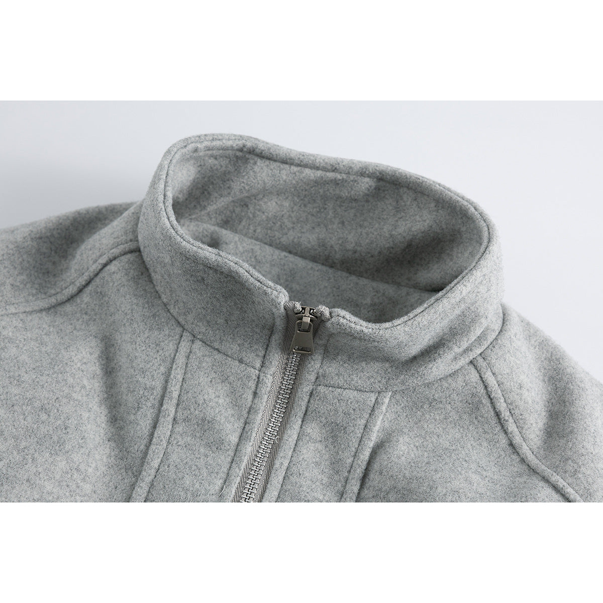 Close-up of a gray jacket's stand collar, front zipper, and seam details.