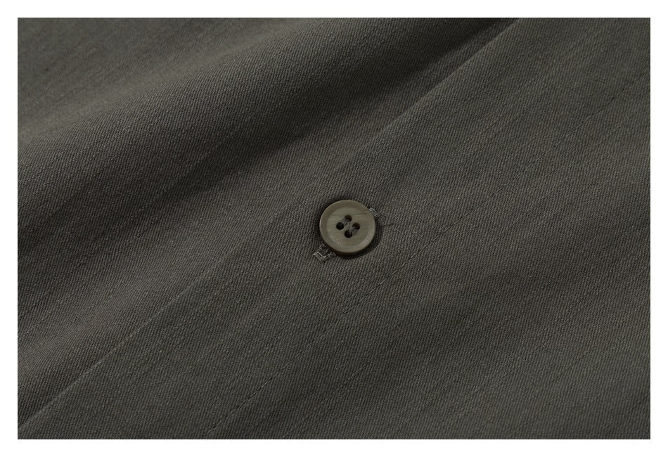 Macro view of a dark olive garment button and stitched fabric.