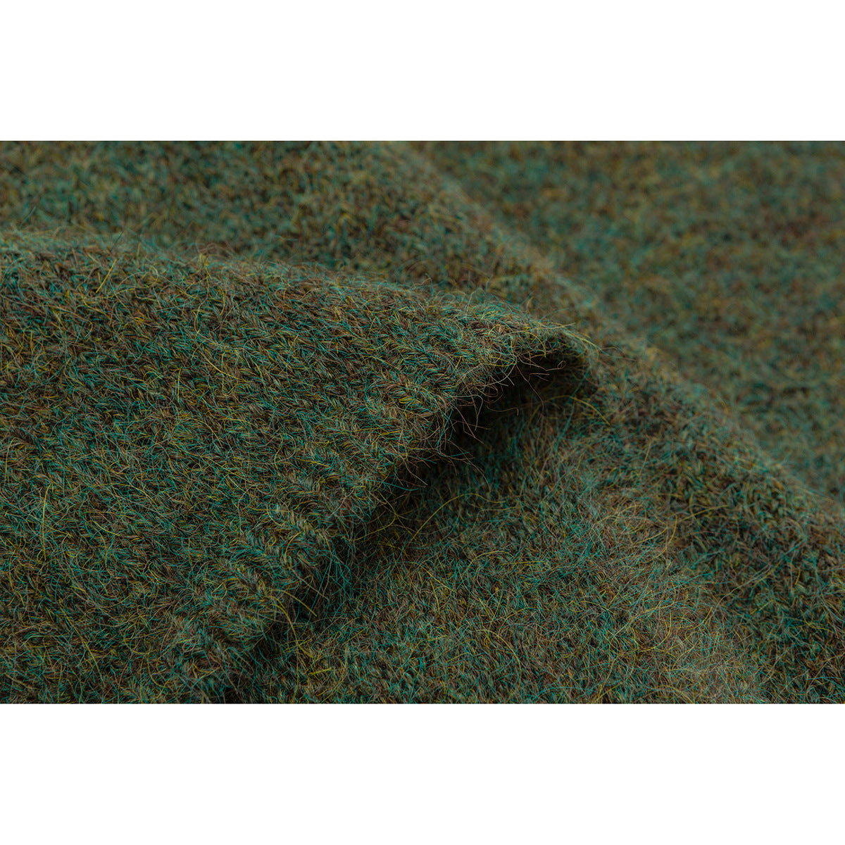 Close-up of fuzzy green-brown knit fabric folded over itself, highlighting its textured edge.