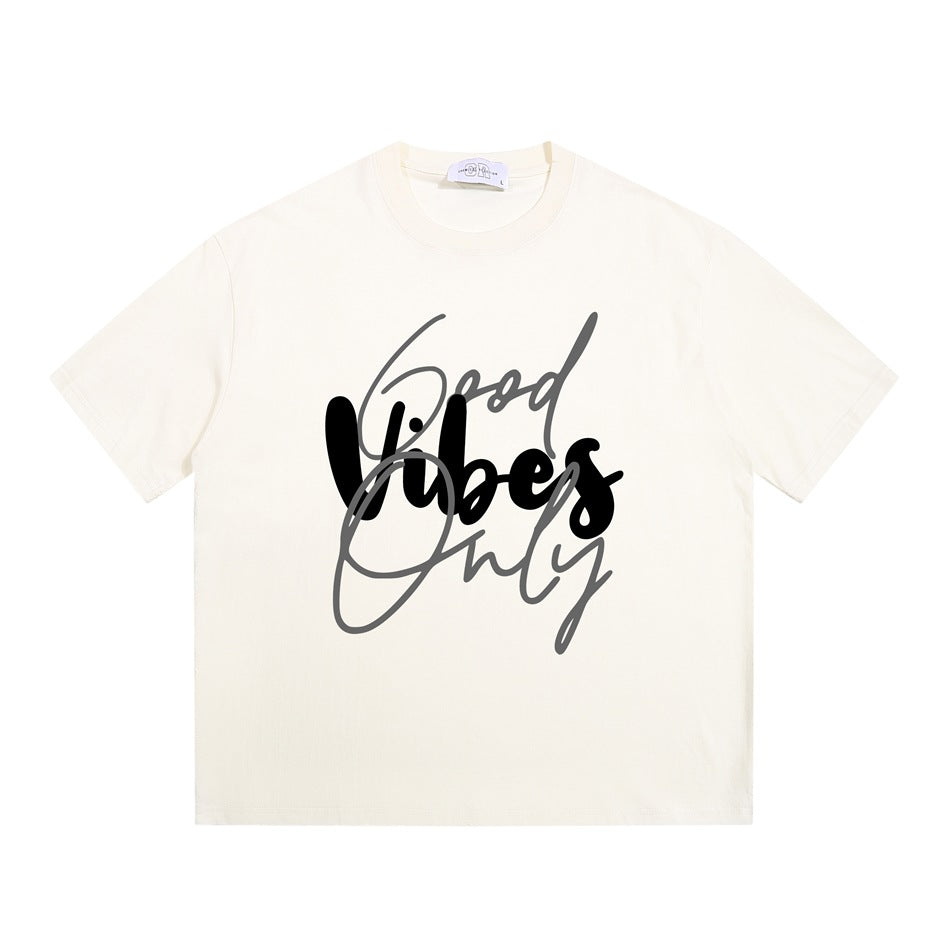 Apricot cream short-sleeve crew-neck T-shirt with black and gray 'Good Vibes Only' script graphic, flat front view