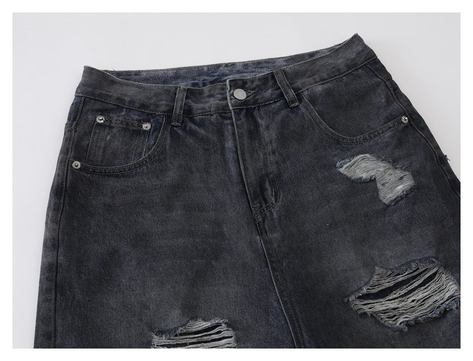 Cropped front view of charcoal jeans showing the waistband, pockets, and frayed distressed patches.