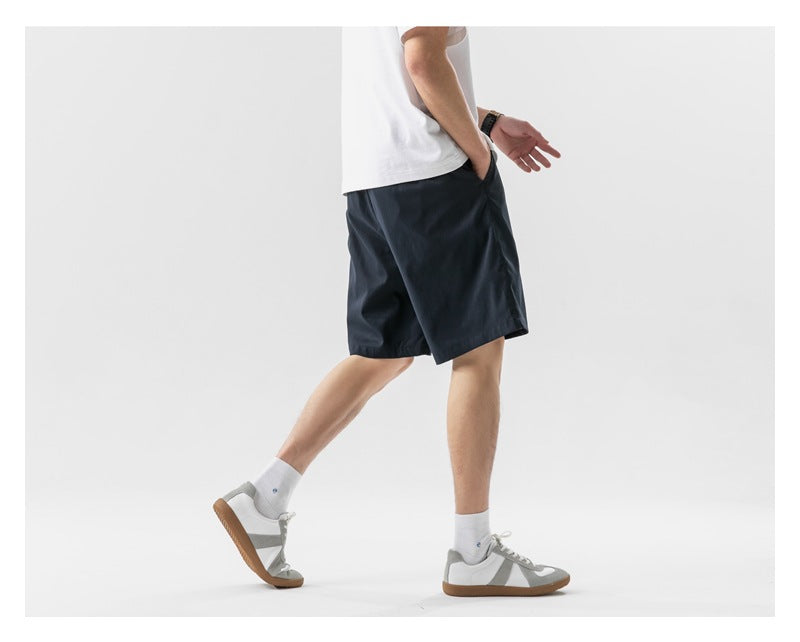 Cropped model wearing dark navy shorts, shown from the side and back while walking.