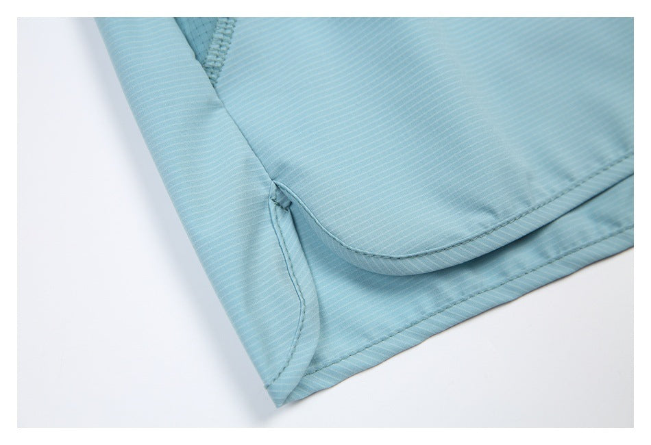 Close-up of aqua shorts showing the curved hem edge and layered side seam.