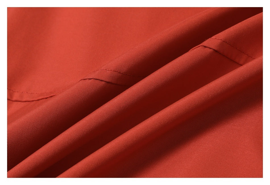 Close-up of rust-red fabric folded to show its surface and stitched seam.