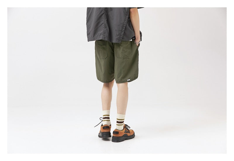 Rear view of a model wearing dark olive shorts with two back patch pockets.