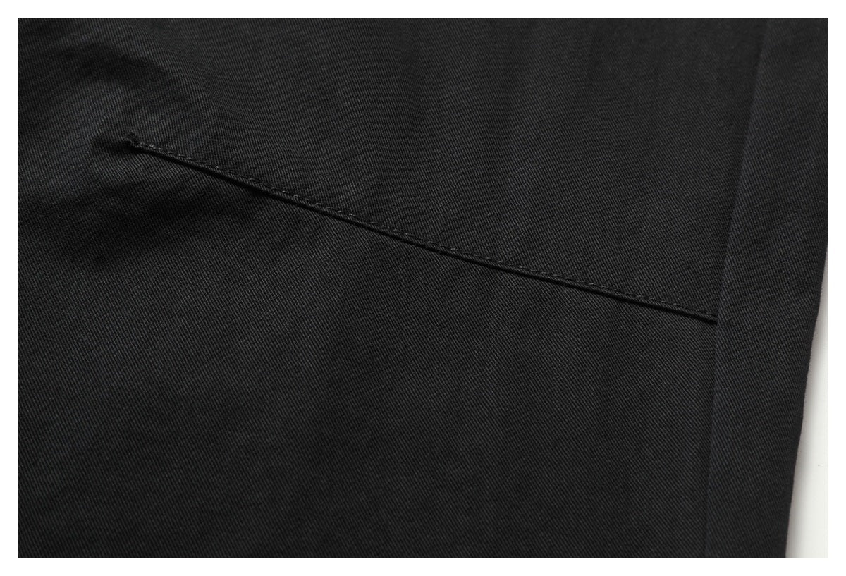 Close-up of a black garment with a narrow slanted welt pocket opening.