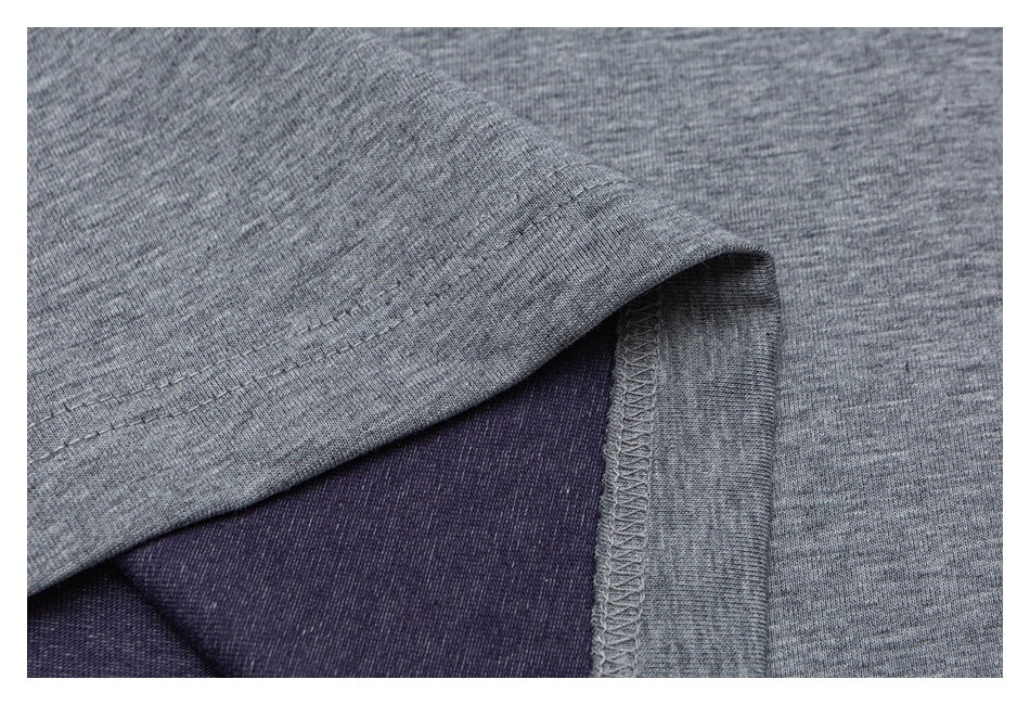 Close-up of a heather-gray shirt hem with visible stitching and dark purple fabric beneath.