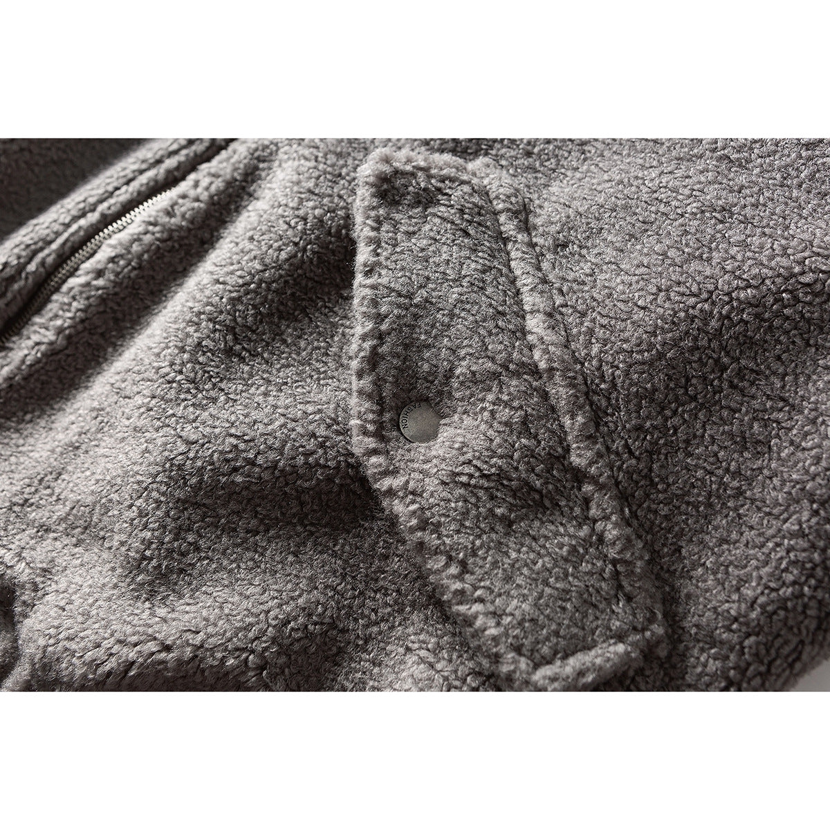 Close-up of a gray textured jacket showing a snap-fastened pocket flap beside the zipper.