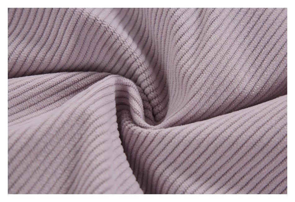 Macro view of the pale mauve garment's plush, wide-ribbed corduroy texture.