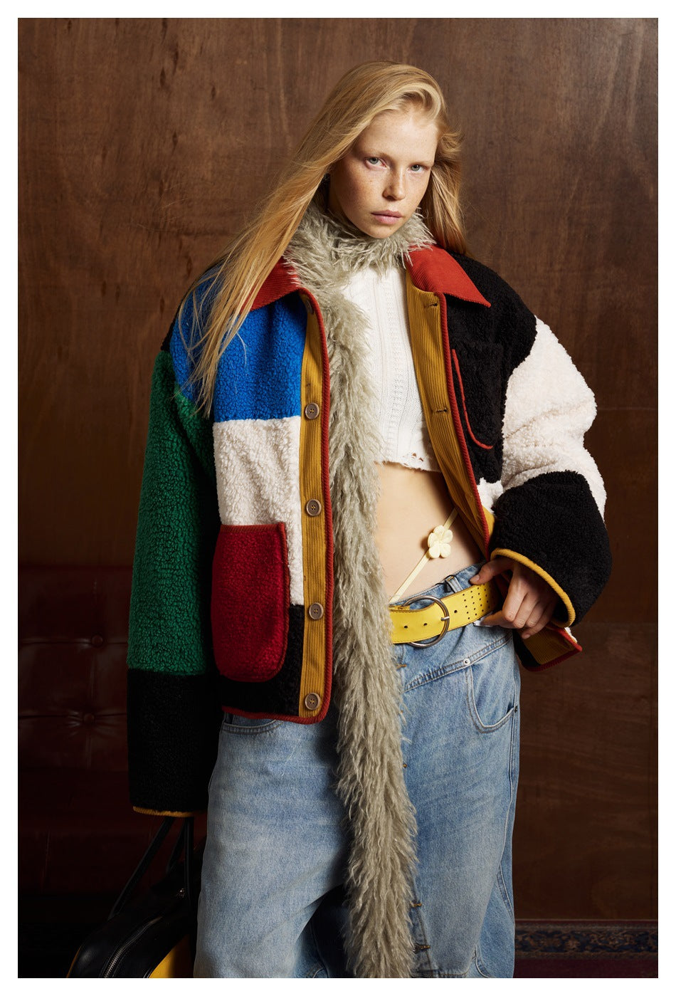 Model wearing a multicolor fleece jacket with red collar, button front and patch pockets, paired with jeans.