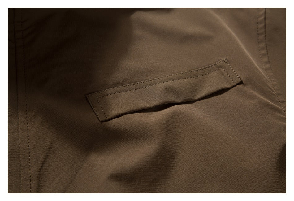 Close-up of a narrow stitched tab on dark brown garment fabric.