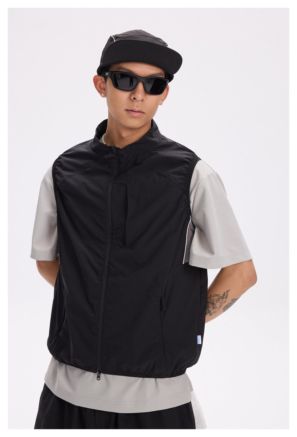 Front view of a model wearing a black zip-front vest over a light gray T-shirt.