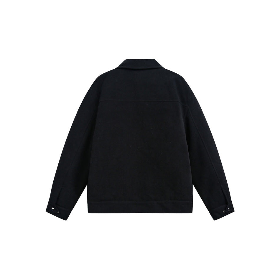 Back view of a black jacket with a short collar and snap-button cuffs.