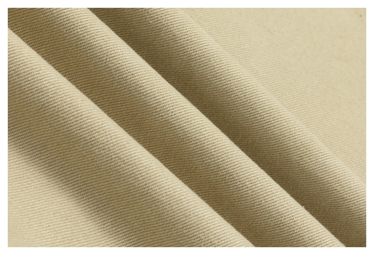 Close-up of beige twill fabric folded into soft ridges, showing its diagonal weave.