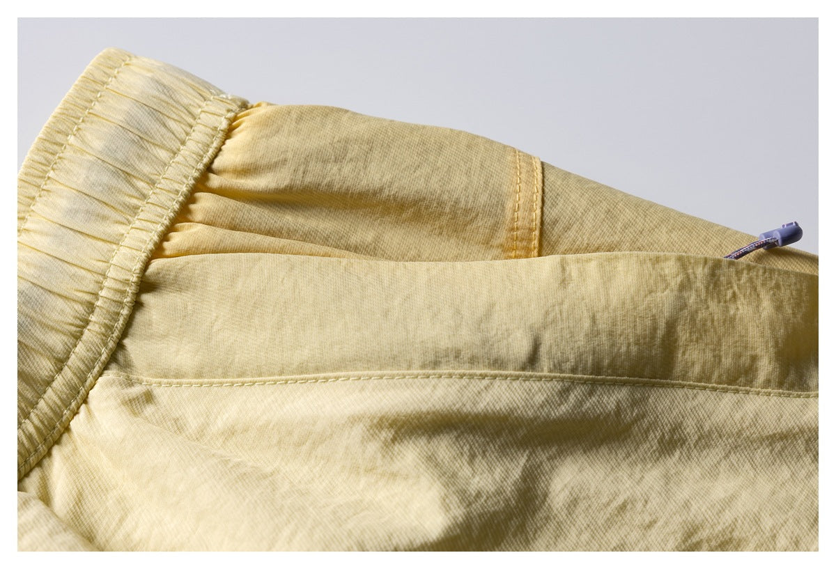 Close-up of pale yellow shorts showing the rear pocket seam and elastic waistband.