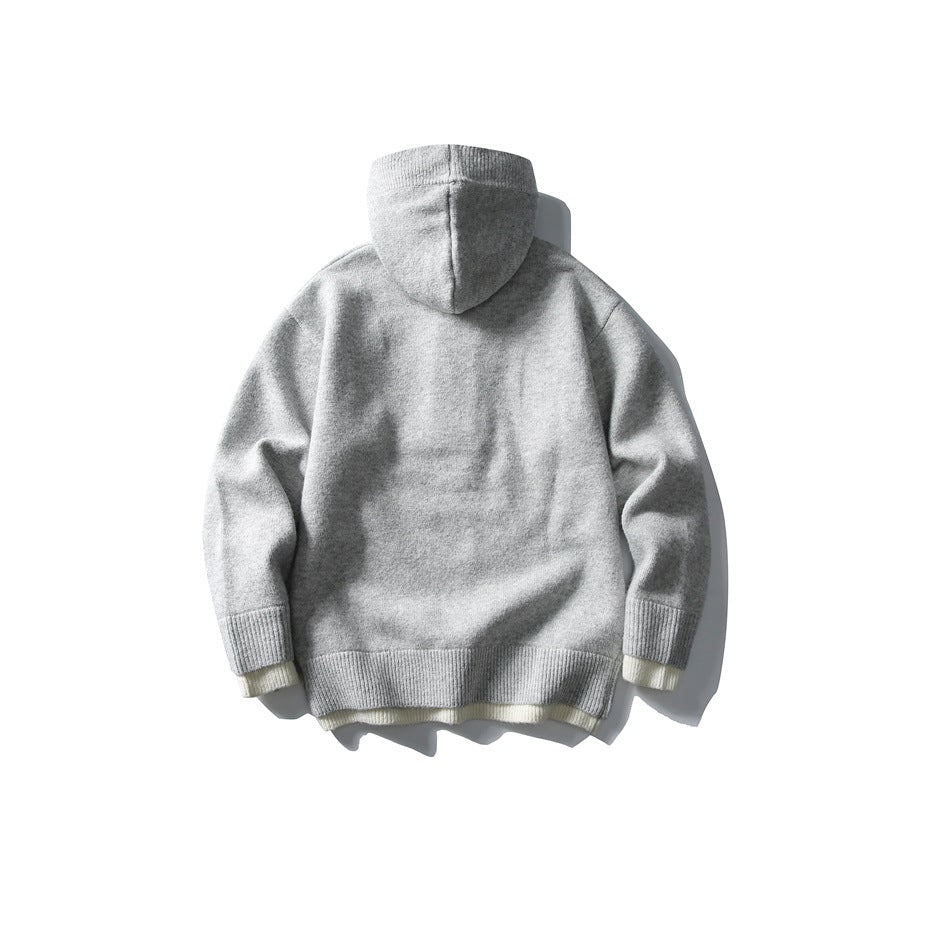 Back view of a light gray hooded knit top with ribbed cuffs and hem and a pale contrasting underlayer.