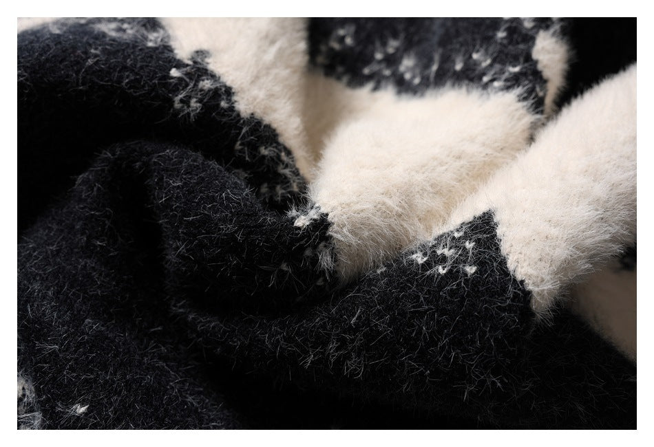 Close-up of a fuzzy black and ivory knit garment showing its soft texture and color-blocked pattern.