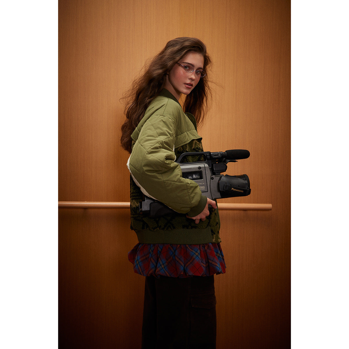Side view of a model wearing an olive quilted bomber jacket with a dark patterned body and cream sleeve accents.