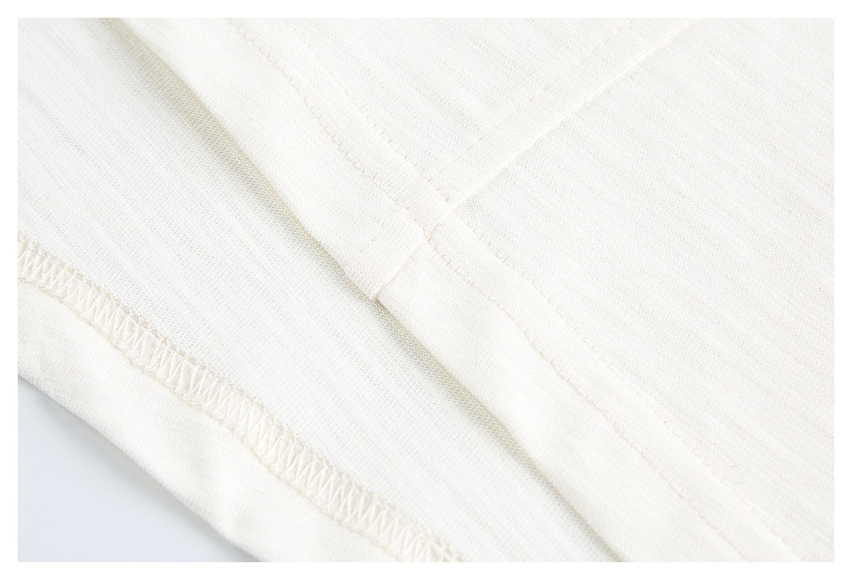 Close-up of off-white knit garment showing an overlocked edge and stitched seam.