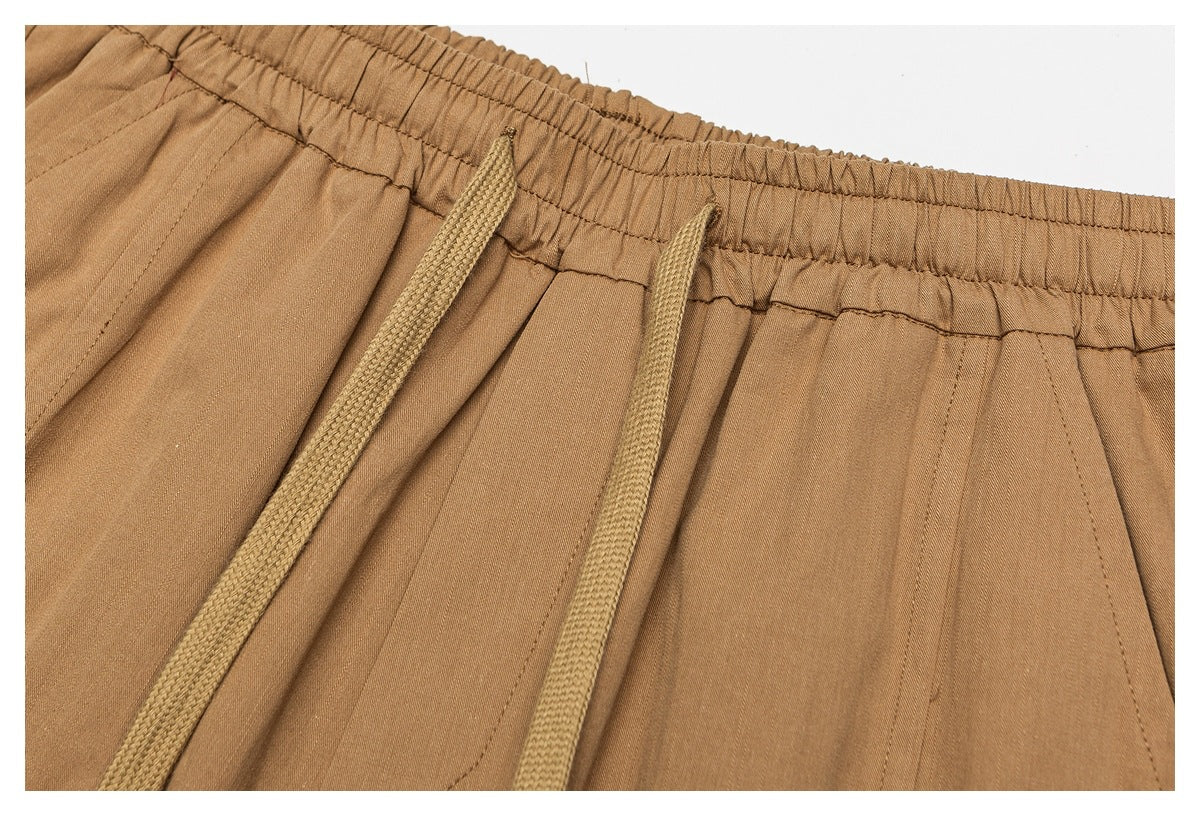 Close-up of tan trousers with an elastic waistband and matching drawstring.