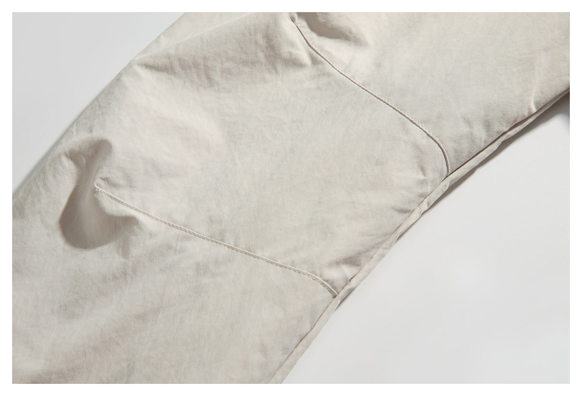 Close-up of a light beige garment showing curved panel seams and a stitched pocket edge.