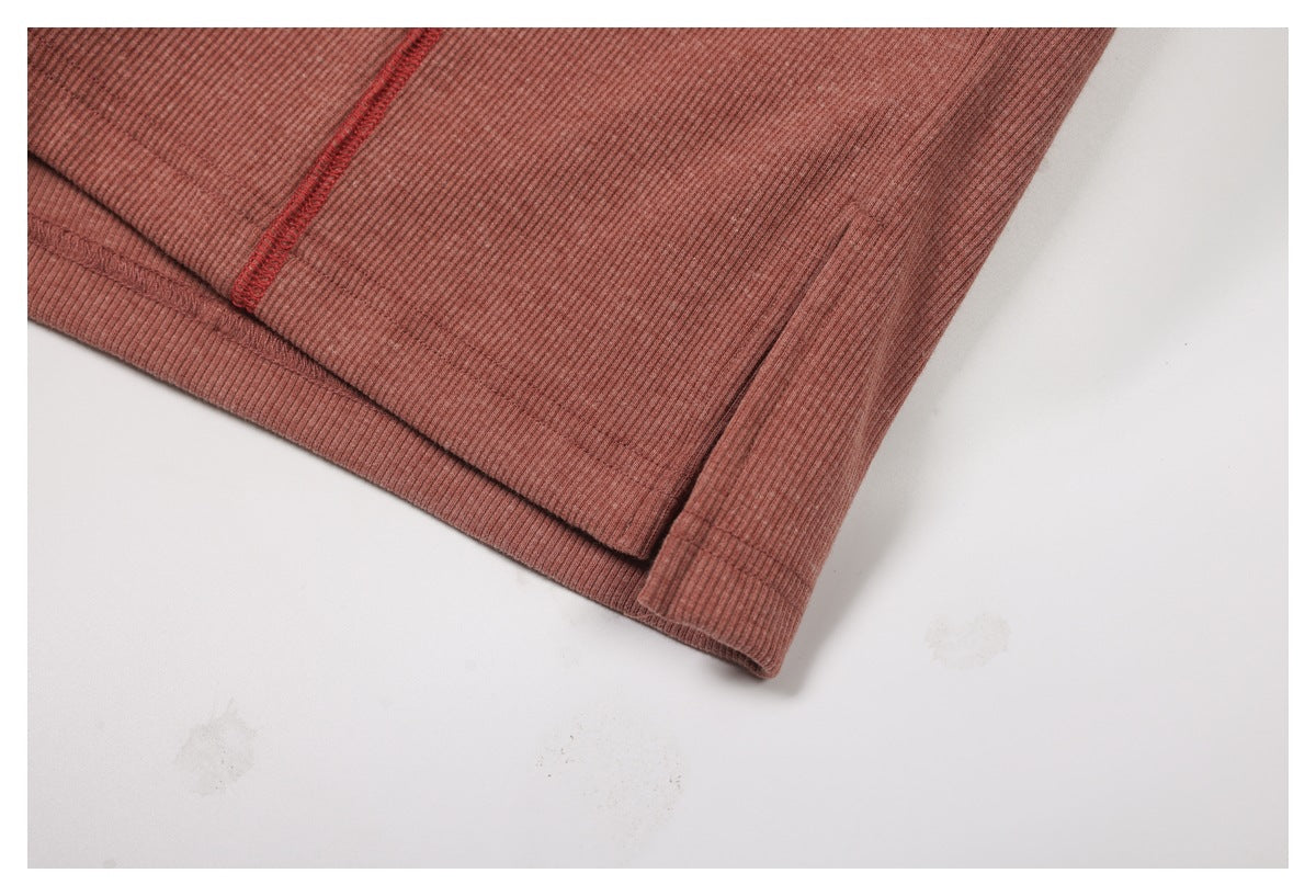 Close-up of the dusty rose top's hem and seam with contrasting red overlock stitching.