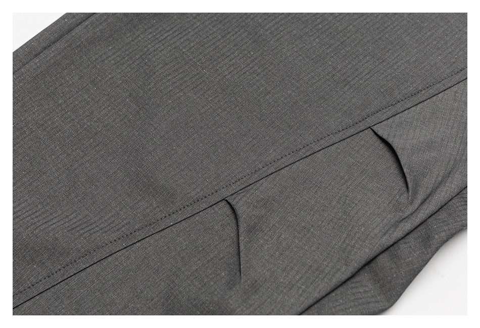 Close-up of dark gray trousers showing an angled seam and two narrow pocket openings.