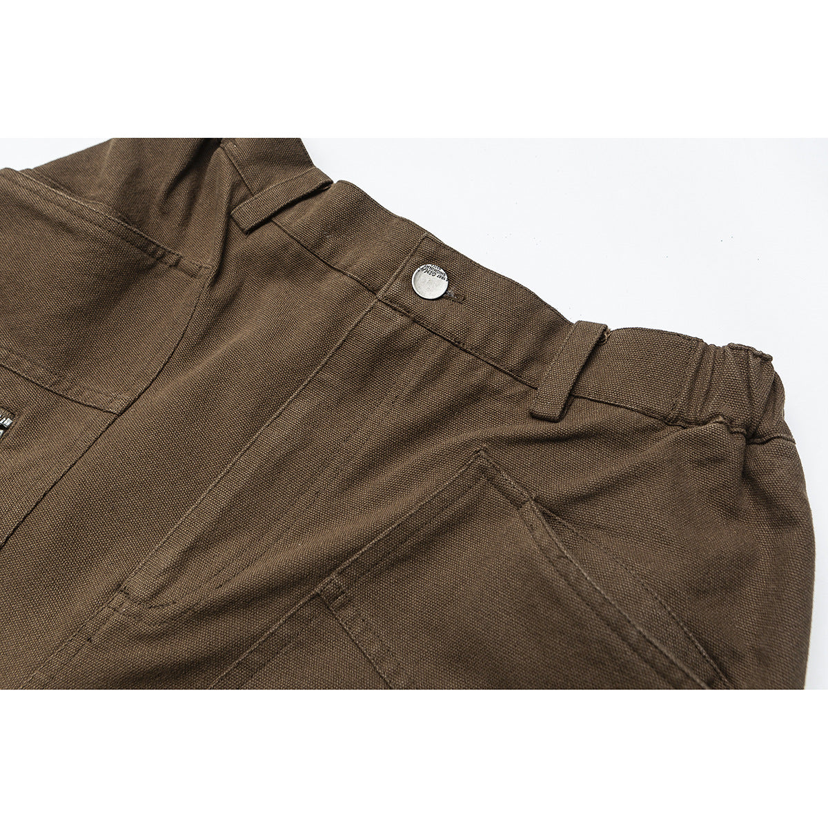 Close-up of brown trousers showing a buttoned waistband, belt loops, stitching, and a slanted pocket.