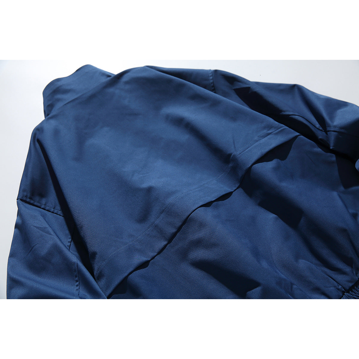 Close view of the navy jacket’s back yoke, seams, and sleeve laid flat.