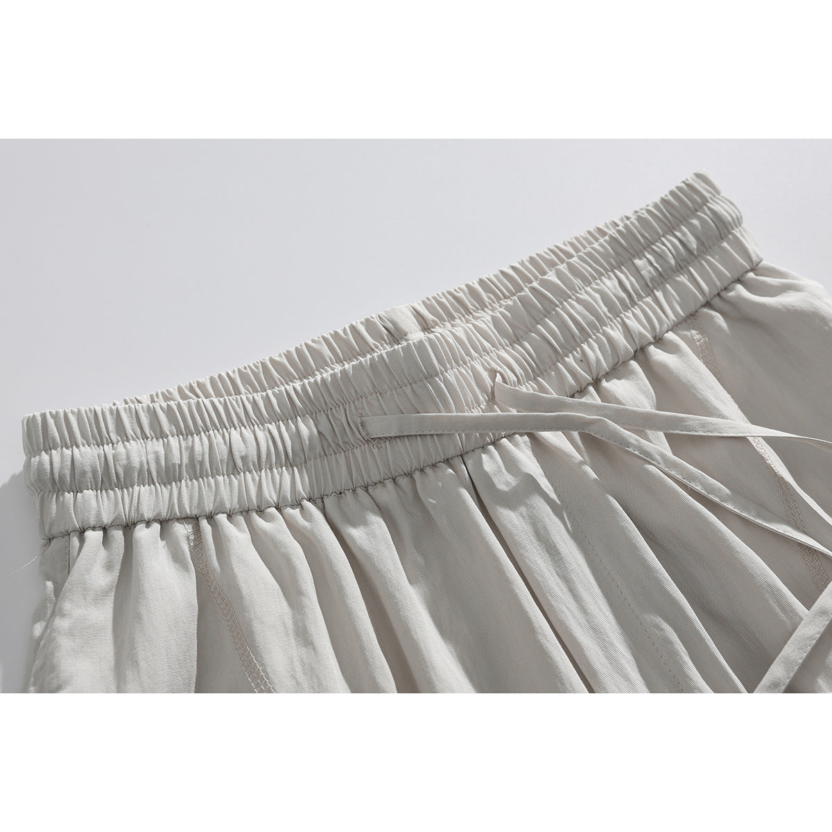 Close-up of off-white shorts showing the gathered elastic waistband and matching drawstring.