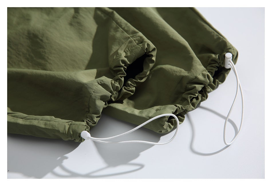 Olive-green pant hem with gathered fabric, white drawcords, and cord locks.