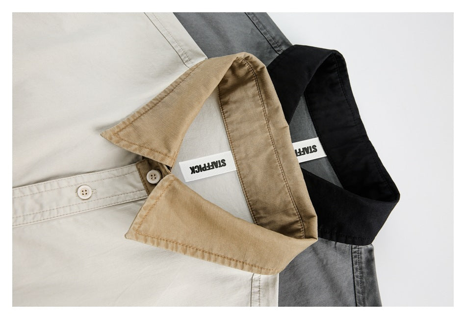 Close-up of overlapping collars on light, gray, and black short-sleeve shirts.