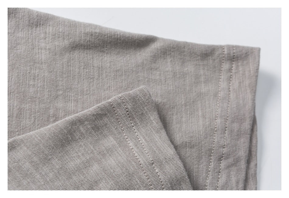 Close-up of a light gray garment edge with a neatly stitched folded hem.